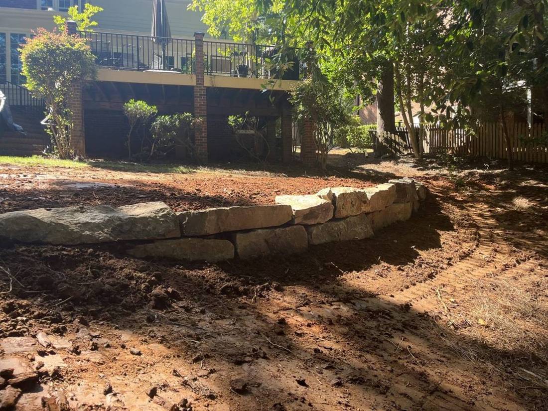 Boulder retaining wall with fresh grading below a deck