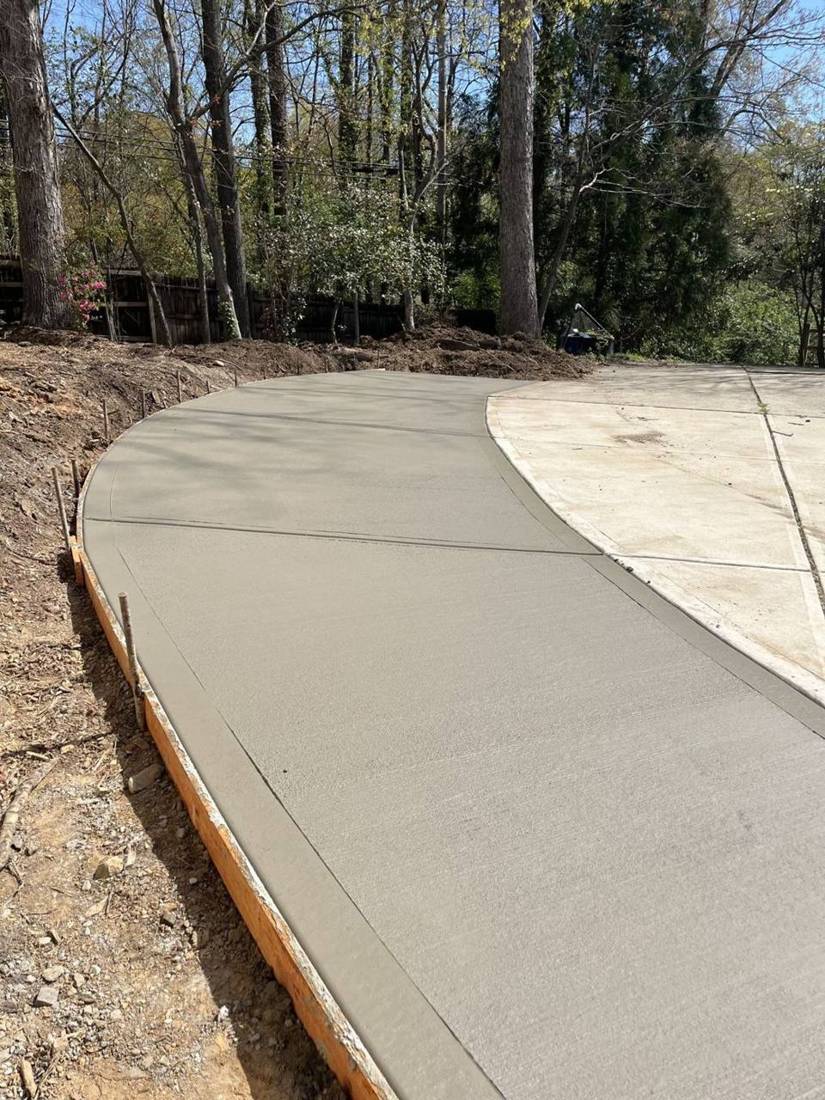 Fresh broom-finished concrete driveway curving along the yard
