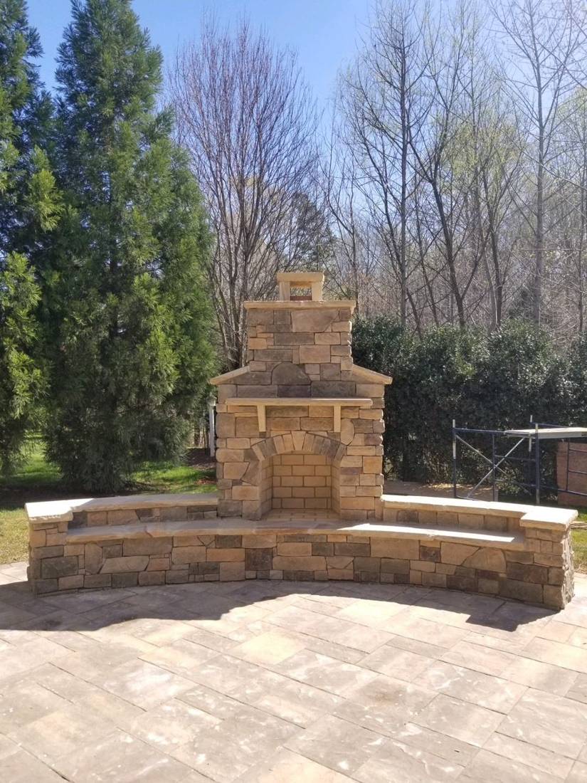 Stone fireplace with curved seat wall on a paver patio