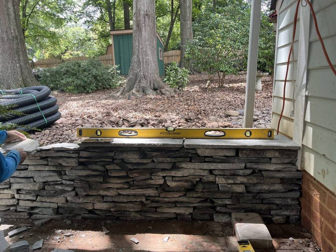 Stacked stone seating wall being leveled